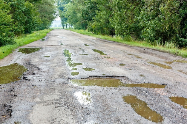 アスファルト上の石で道路に穴が開いている 道路のアスファルト面が破壊されている 道路の状態が悪く、修理が必要 道路の建設と修理