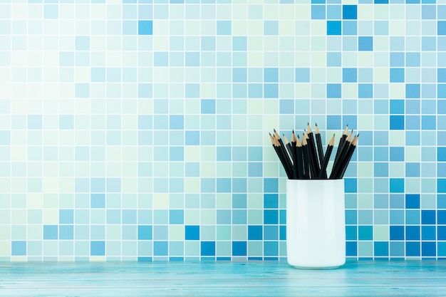 potloden in witte keramische bekers op blauw kantoor.