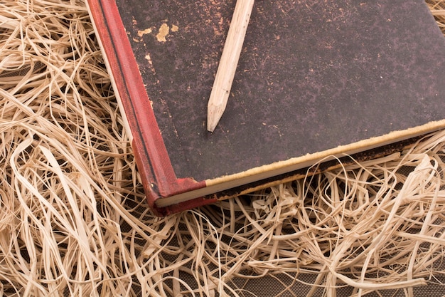 Potlood op een boek over stroachtergrond