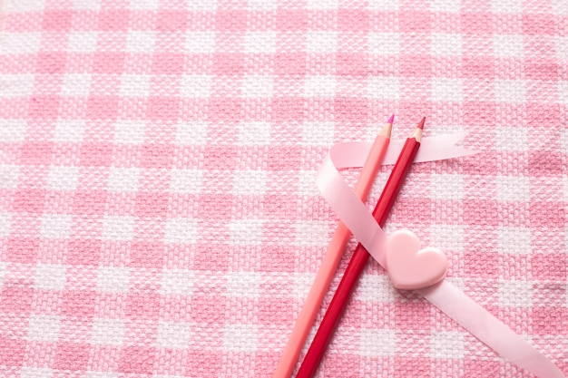 Potloodpaar in liefde op de roze achtergrond van de tafelkleedtextuur