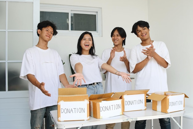 Photo potrait of cheerful donation volunteer team applaud and presenting donation box for charity event