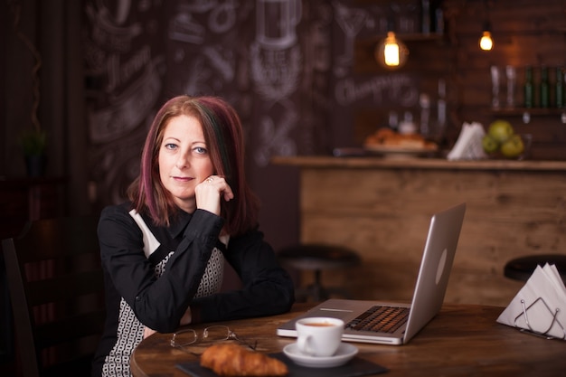 Potrait van volwassen vrouw die haar laptop in restaurant met behulp van. Ontspannen in de kroeg.