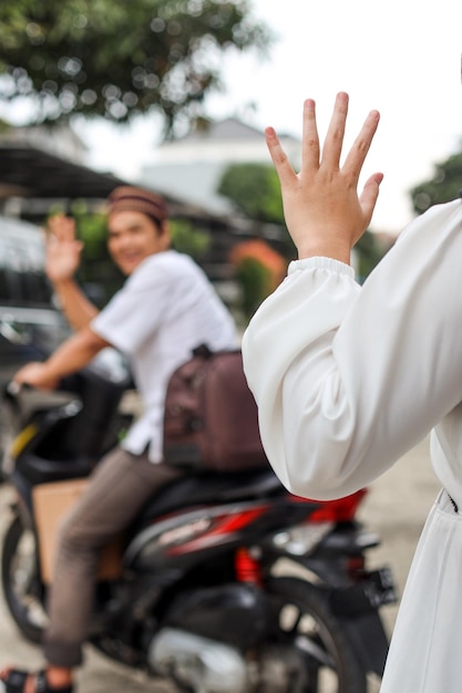 Potrait of young muslim man waving hand saying goodbye to travel mudik at eid mubarak moment