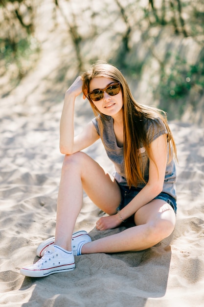 Potrrait of fashionable young teen in sunglasses posing for camera on the beach