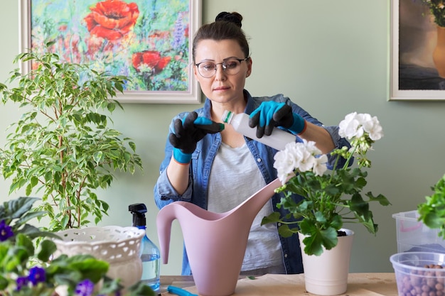 Potted plant care woman using liquid mineral fertilizer for watering