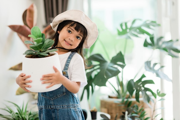 かわいい子供が持っている家で鉢植えの植物