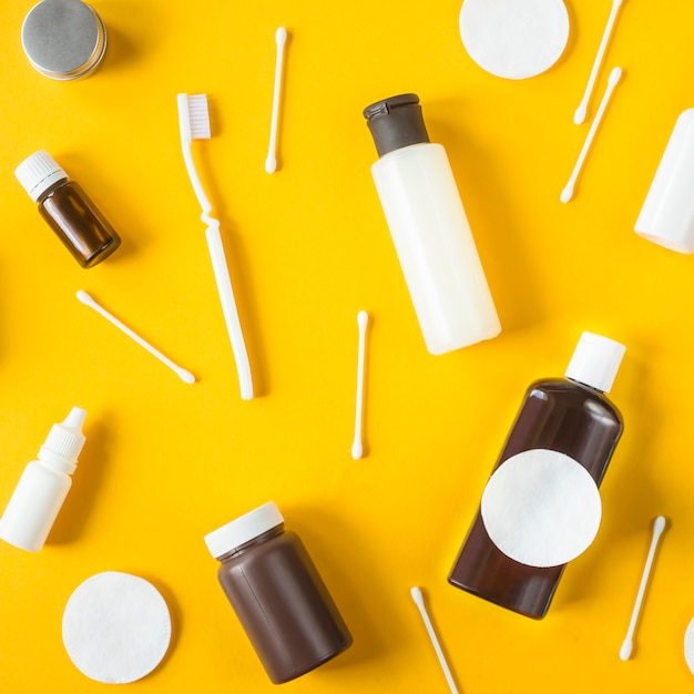 Potten en containers met cosmetica, wattenstaafjes en schijven en tandenborstel verspreid