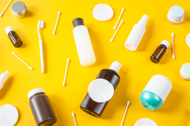 Potten en containers met cosmetica, wattenstaafjes en schijven en tandenborstel verspreid