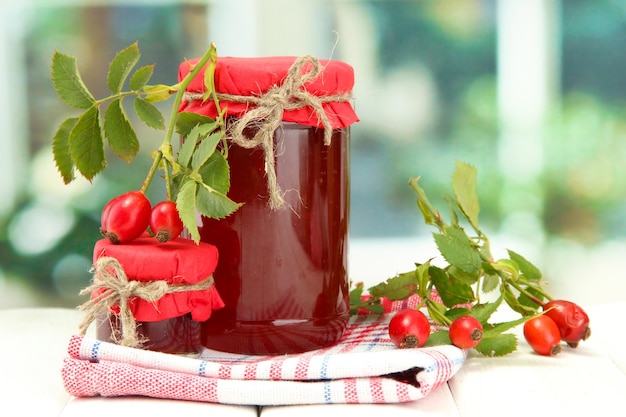 Potten met hippe rozenjam en rijpe bessen op houten tafel