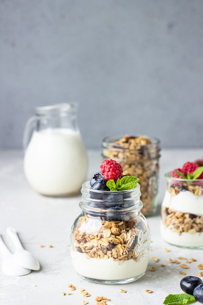 Potten met smakelijke parfait gemaakt van granola, bessen en yoghurt op steen grijze tafel.