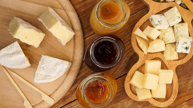 Potten zelfgemaakte jam en een verscheidenheid aan kazen op een houten tafel Kaasbord