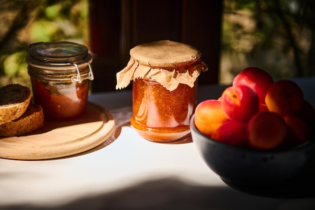 Potten zelfgemaakte jam heerlijke rijpe rode abrikozen in een blauwe keramische kom op een tafel in de rustieke zomerkeuken Stilleven