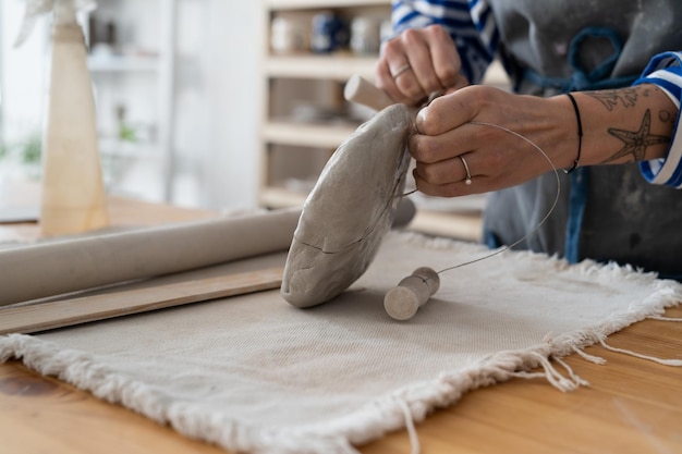 Pottenbakker beeldhouwer die klei snijdt met het touwtje in werkplaats te koop in winkel