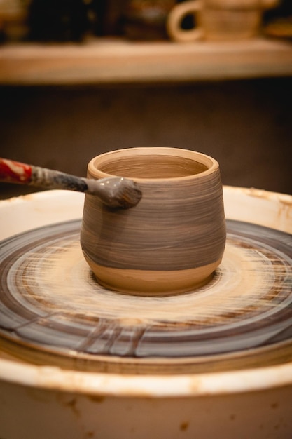 Pottenbakker bezig met pottenbakkerswiel met klei Proces van het maken van keramisch servies in aardewerkatelier Handwerk en kunstconcept