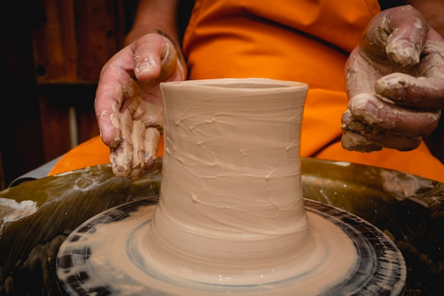 Potter bezig met pottenbakkerswiel met klei. proces van het maken van keramisch servies in de pottenbakkerij. handwerk en kunst concept.