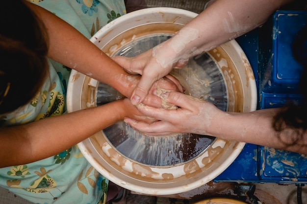 Potter bezig met pottenbakkerswiel met klei. Proces van het maken van keramisch servies in de pottenbakkerij. Handwerk en kunst concept.