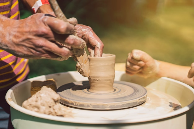 Potter die een klei-object maakt op een aardewerkwiel in de buitenlucht ambachtsman die klei vormt met de handen op potten...