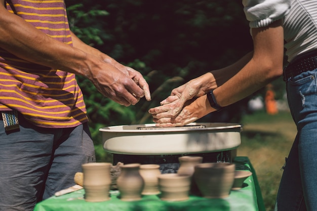 Potter die een klei-object maakt op een aardewerkwiel in de buitenlucht ambachtsman die klei vormt met de handen op potten...