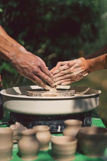 Potter die een klei-object maakt op een aardewerkwiel in de buitenlucht ambachtsman die klei vormt met de handen op potten...