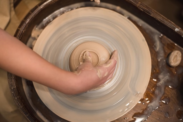 Foto ragazza vasaio lavora sulla ruota del vasaio facendo pentole in ceramica con l'argilla in un laboratorio di ceramica art and hobby concept