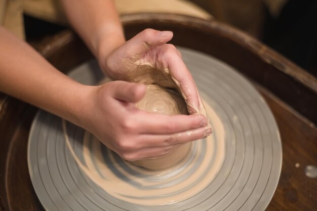 Photo potter girl works on potters wheel making ceramic pot out of clay in pottery workshop art and hobby concept