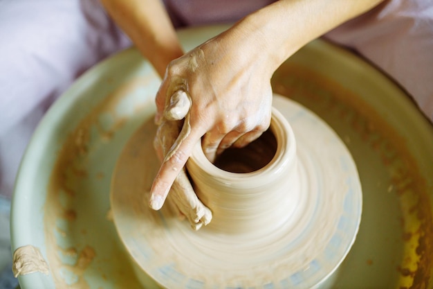 Potter handen beeldhouwt een vaas uit klei op een potter close-up