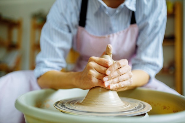 Potter hands sculpts a vase from clay on a Potter close up