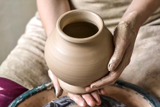 Potter houdt meer vast aan het bakken van een witte kleikruik. Beeldhouwer beeldhouwt pottenproducten van witte klei. Meester houdt met lege handen een aarden vat open. Workshop aardewerk. Oekraïne, nationale tradities