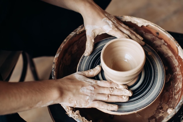 Potter makes a clay jug on a potter's wheel Handmade