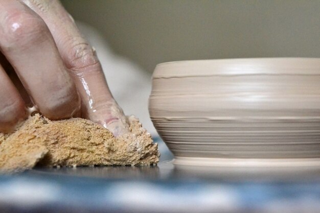 Foto il vasaio chiude un vaso di terracotta. mani macchiate nell'argilla e nel piatto di argilla