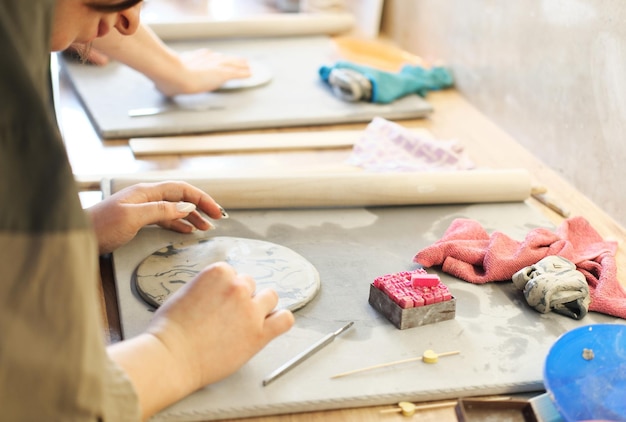 Гончар делает надпись или рисунок на мокрой глиняной тарелке Концепция ручного труда или малого бизнеса