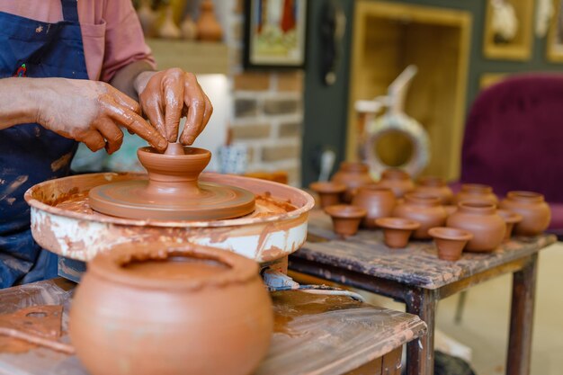 Photo potter makes a mug from clay on a potter's wheel