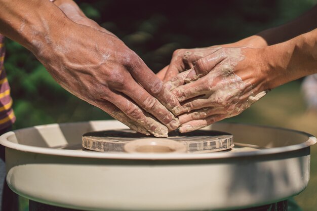 Potter che fa un oggetto di argilla sul tornio in ceramica all'aperto artigiano che modella l'argilla con le mani su...