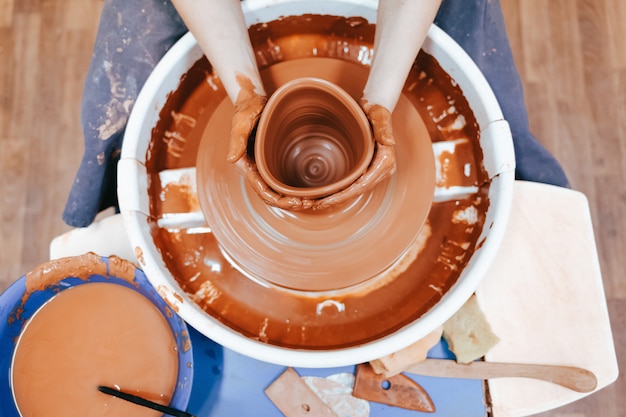 ろくろの後ろにある陶芸家が粘土を作り、陶器料理を作ります