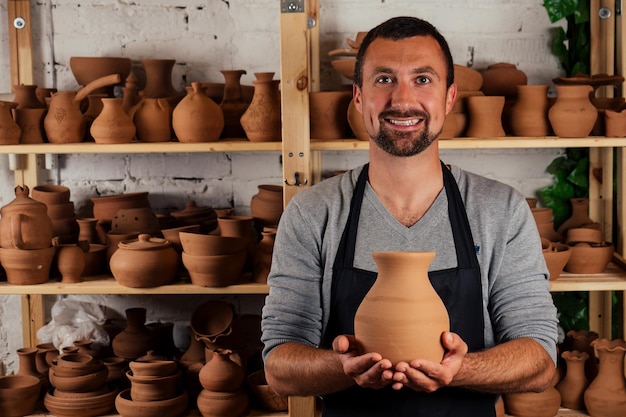 Potter professional happy man working with brown clay in workshop . businessman artist trade handmade pot shop.