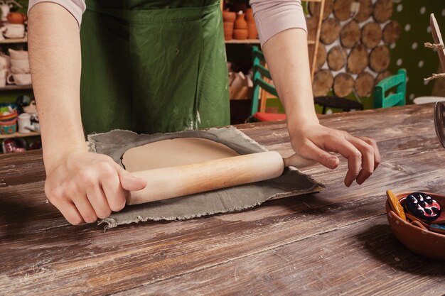 Potter rolls a brown clay