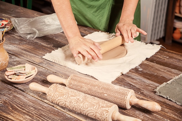 Potter rolls a brown clay