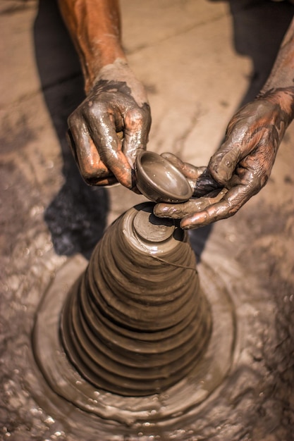 A potter's hands are working on a stack of clay.