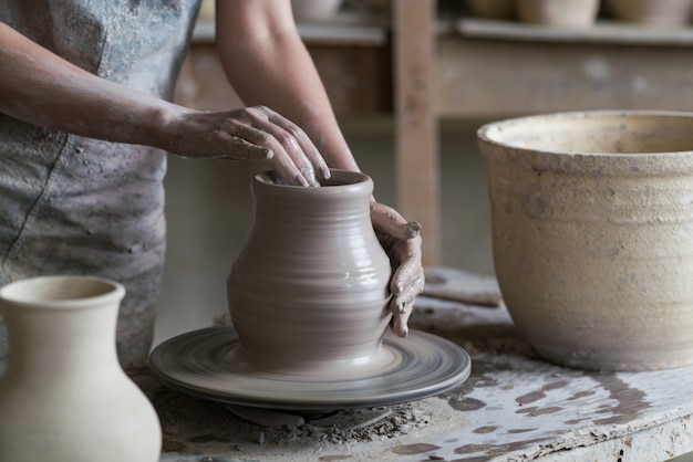 陶工は、ろくろの上に花瓶を彫る