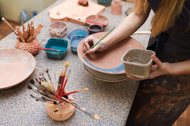 Foto la donna del vasaio dipinge un piatto di ceramica.