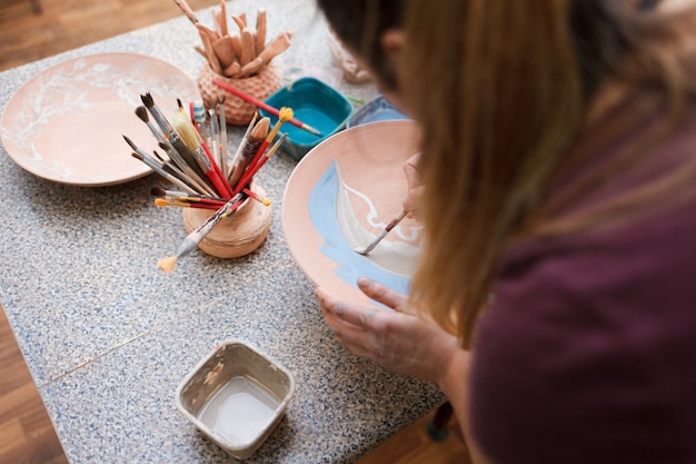 Potter woman paints a ceramic plate.