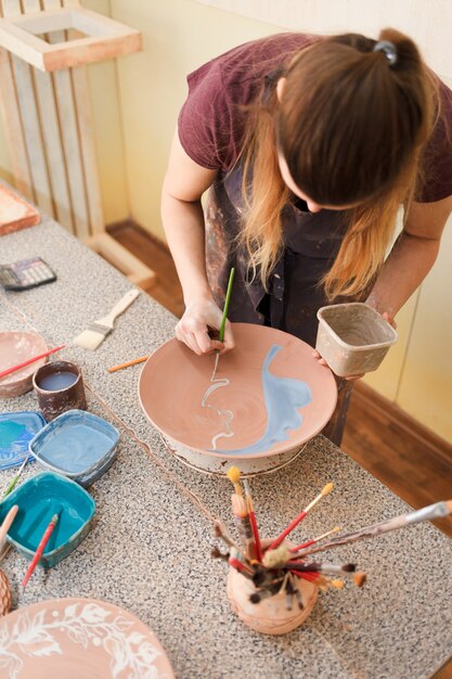 Potter woman paints a ceramic plate.