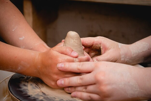 Photo potter working on potters wheel with clay. process of making ceramic tableware in pottery workshop. handicraft and art concept.