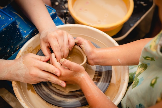 Potter working on potters wheel with clay. Process of making ceramic tableware in pottery workshop. Handicraft and art concept.