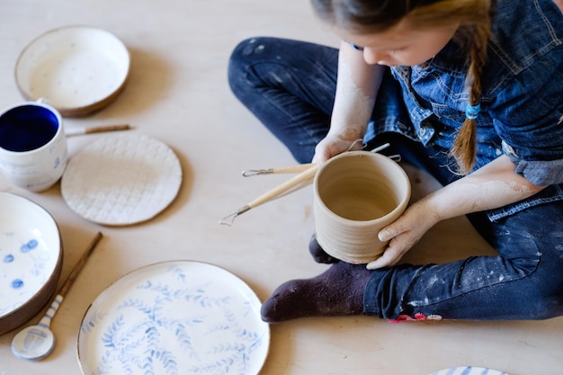 写真 手作りの皿や食器の品揃えの中に座っている陶器アートセラピークリエイティブリラックスレジャー少女