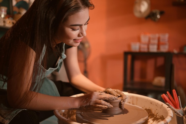 Photo pottery artist young female making a piece of clay molding calmly and meticulously