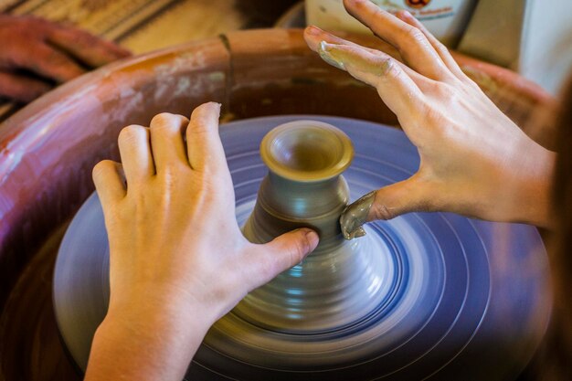 Pottery class at art school. clay on pottery wheel, clay bowl\
production, hands producing clay vase