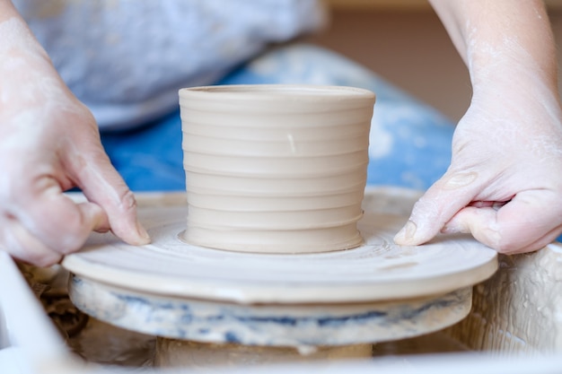 Pottery handcraft hobby. hands forming and shaping clay jug on potter wheel