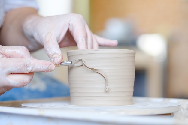 Pottery handicraft skills. traditional art of creating ceramics. potter modeling clay jug on turning wheel