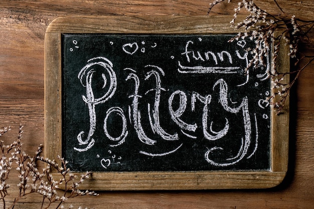 Pottery hobby Vintage chalkboard with lettering funny pottery with dry flowers on wooden background Top view DIY pottery workshop advertising